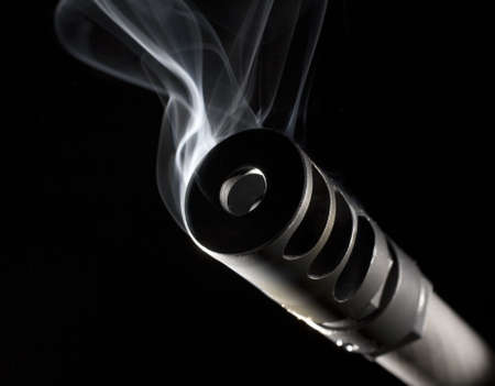 rifle barrel that is spewing out smoke on a black backgroundの写真素材
