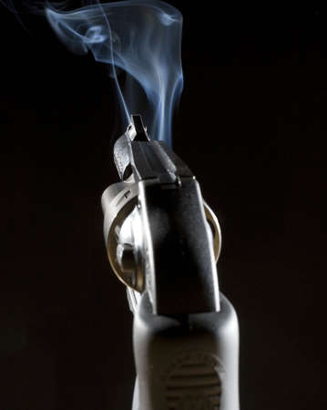 handgun in the dark that is belching a lot of smokeの写真素材