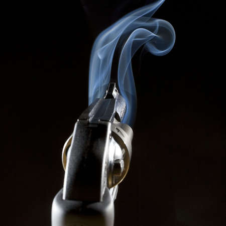 revolver in the dark that is emitting a blue smokeの写真素材
