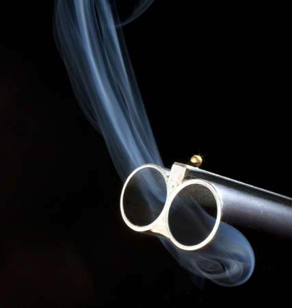 Both barrels of a double barrel shotgun billowing smokeの写真素材