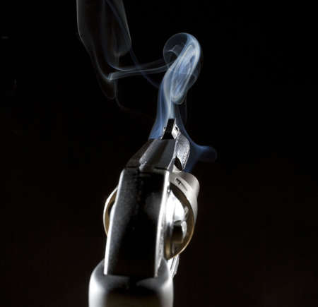 handgun that is smoking after a shot in the darkの写真素材