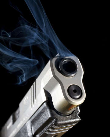 Semi-automatic pistol releasing smoke after a shot has been takenの写真素材