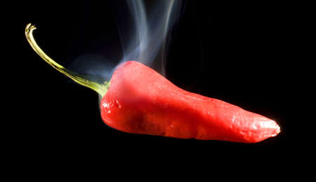 Red pepper on black so hot that smoke is risingの写真素材