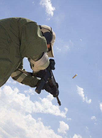 Man seen from underneath shooting an assualt rifle with brass in the air