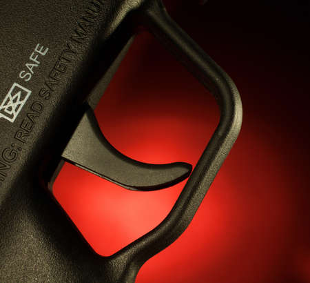 Assault rifle trigger that is with a red backgroundの写真素材