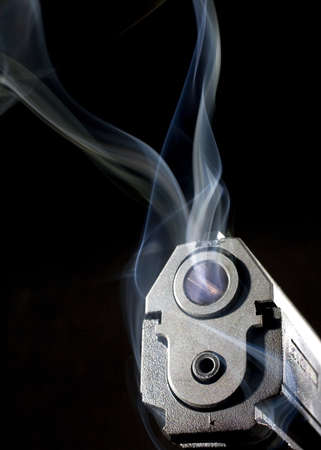 Smoke that is hanging around the muzzle of a handgunの写真素材