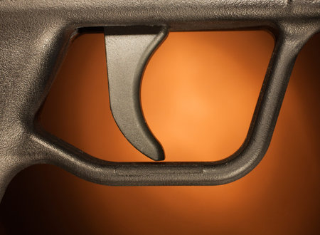 Trigger on an assault rifle with a brown background