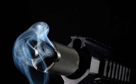 Muzzle on an assault weapon that is smoking in the darkの写真素材