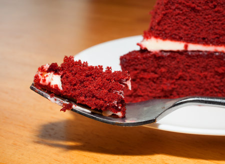 Big fork full of red velevet cake with some behind