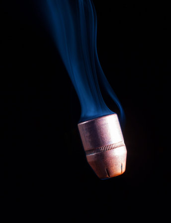 Copper handgun bullet going down with smoke behind