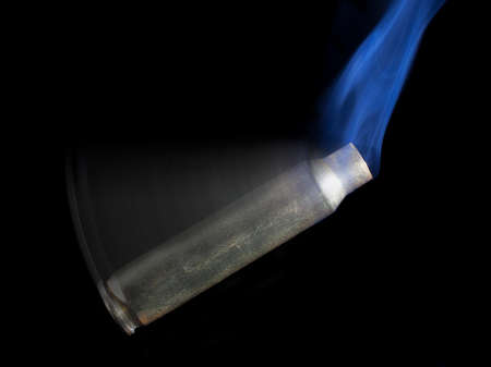 Rifle cartridge that has been shot and the brass is rotating with smokeの写真素材