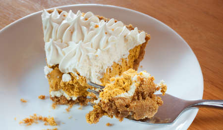 Fork full of whipped pumpkin pie on a white plateの写真素材