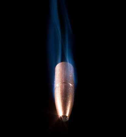 Copper plated bullet with trailing smoke that looks like it is coming at the viewerの写真素材