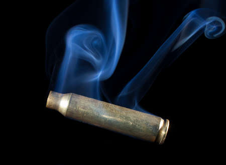 Brass case from a cartridge that has smoke on a black backgroundの写真素材