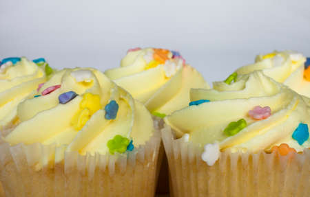 Yellow frosted cupcakes up close with a white backgroundの写真素材