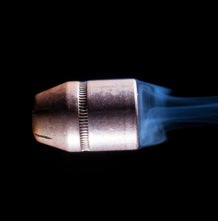 Copper bullet with smoke behind on a black backgroundの写真素材
