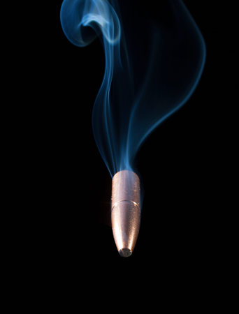 Copper colored bullet with smoke behind heading toward the viewer