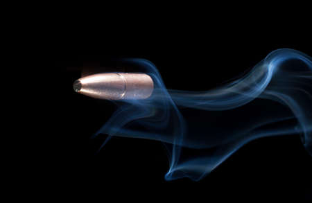 Copper plated bullet on a black background with smokeの写真素材
