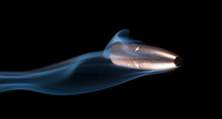 Bullet with a copper jacket and smoke on a black backgroundの写真素材