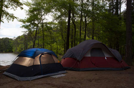 Two nylon tents in a campsite next to a lakeの写真素材