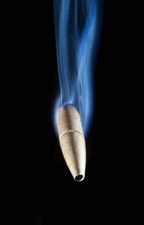 Copper bullet with blue smoke that appears to be flying on a black background
