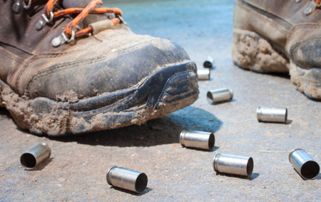 Muddy boots with lots of empty handgun shells around