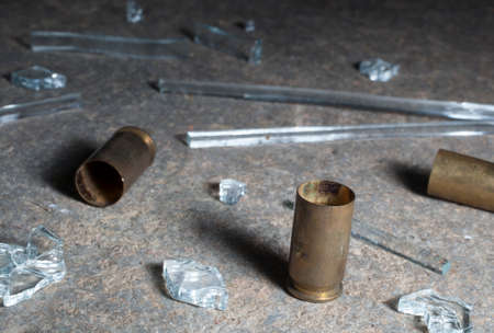 Handgun brass laying on dark concrete with broken glassの写真素材