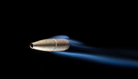 Copper colored bullet that is speeding past the viewer with smokeの写真素材