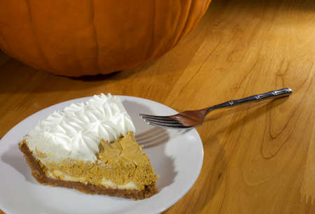 Whipped pumpkin pie on a plate next to a pumpkinの写真素材