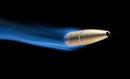 Copper colored bullet on the move with smoke behindの写真素材