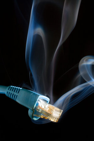 Computer network connector that has smoke rising on a black background