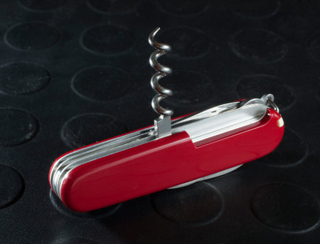Metal corkscrew that is on a small red pocketknife