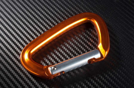 Orange carabiner made for climbing on a graphite backgroundの写真素材