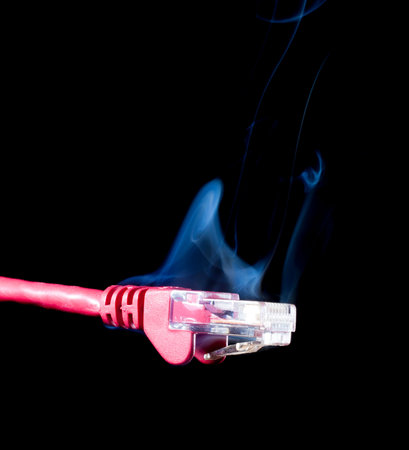 Red network cable on black with smoke rising above