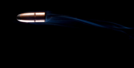 Copper plated bullet with smoke trailing on a black background