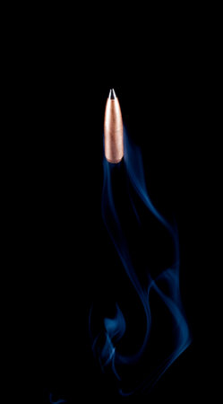 Copper plated bullet with a polymer tip headed up with smoke behind