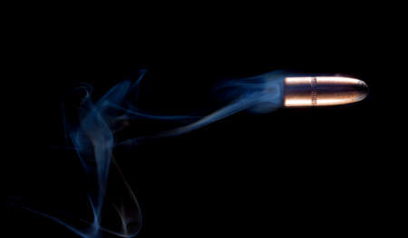 Smoke swirling behind a copper plated lead bullet on a black backgroundの写真素材