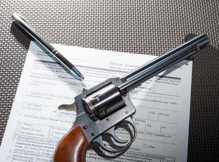 Revolver and a pen resting on background paperwork for a purchaseの写真素材