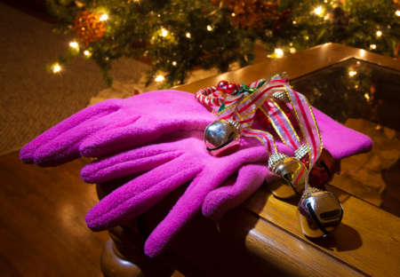 Bright pink gloves on a table with a Christmas tree behindの写真素材