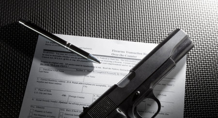 Purchase paperwork for a pistol along with a pen on a mat