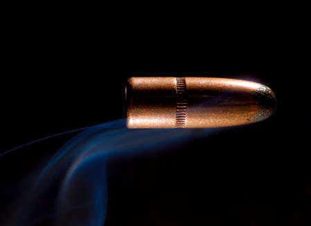 Bullet with copper plating and smoke behind with a black backgroundの写真素材