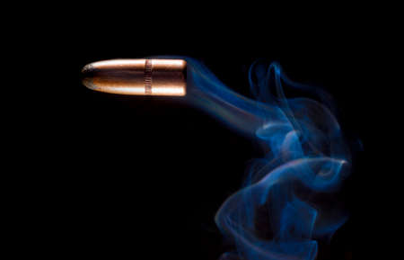 Bullet and blue smoke on a black background の写真素材