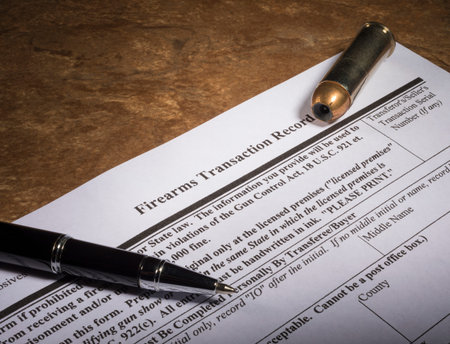 Top of the FBI's NICS background check for gun purchases with a pen and ammo