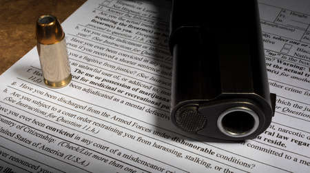NICS check form with dishonorable discharge question and gun with ammoの写真素材