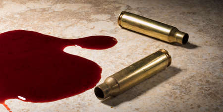 Floor with blood in a pool and empty AR-15 brass casingsの写真素材