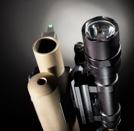 Front of a pump action shotgun with a flashlight attached to the barrel