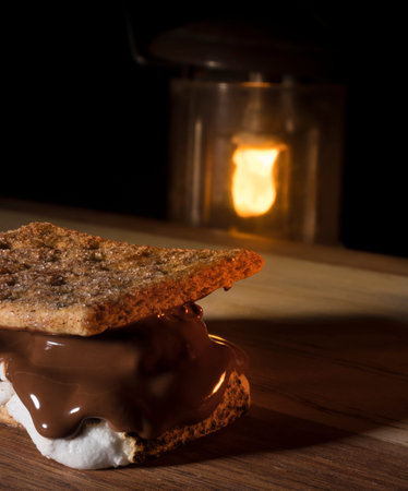 Smore with too much marshmallow with camping lantern behind