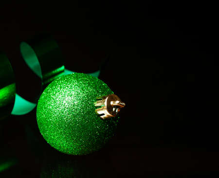 Green Christmas ornament on ribbon on a black surfaceの写真素材