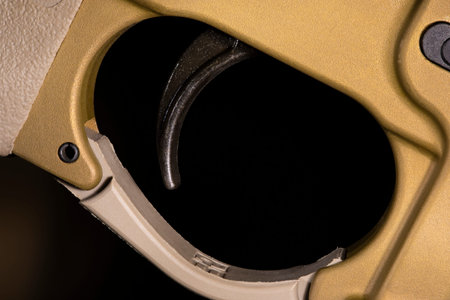 Trigger on an AR-15 in a gold color on a dark background