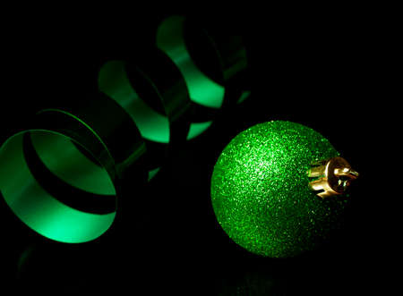 Christmas ribbon curling in the background with a green holiday ornamentの写真素材